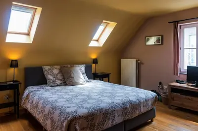 a bedroom with a bed with a blue comforter and two windows at B&B La Clé du Sud in Merelbeke