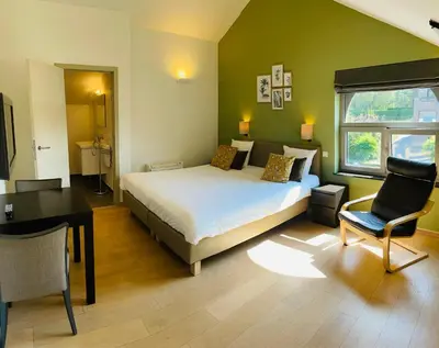 a bedroom with a bed and a desk and a chair at Hotel & Apartments Bibois Leuven in Oud-Heverlee