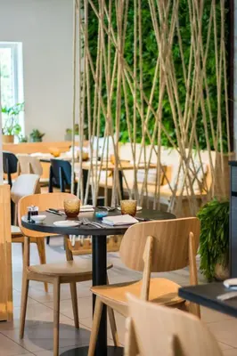 a table and chairs in a restaurant with trees at Hotel & Apartments Bibois Leuven in Oud-Heverlee
