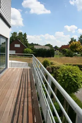 a wooden deck with a white railing on a house at Hotel & Apartments Bibois Leuven in Oud-Heverlee