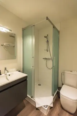 a bathroom with a shower and a sink and a toilet at Hotel & Apartments Bibois Leuven in Oud-Heverlee