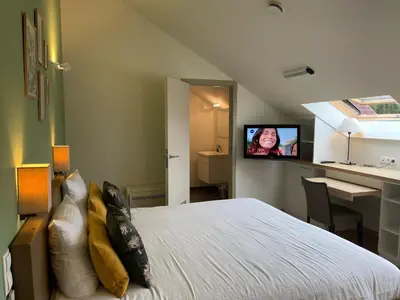 a bedroom with a bed with a tv on the wall at Hotel & Apartments Bibois Leuven in Oud-Heverlee