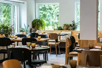 a restaurant with tables and chairs and windows at Hotel & Apartments Bibois Leuven in Oud-Heverlee