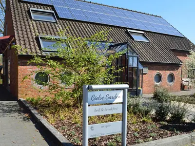 a sign in front of a house with solar panels at B&B Gielse Garden in Gierle
