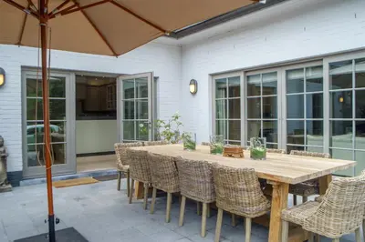 a wooden table with chairs and an umbrella on a patio at Villa Magdalena Eeklo in Eeklo