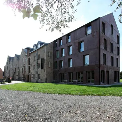 a large brick building with grass in front of it at 'S Hertogenmolens Hotel in Aarschot