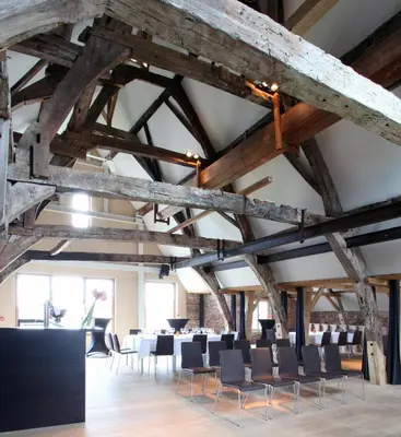 a room with tables and chairs in a building with wooden beams at 'S Hertogenmolens Hotel in Aarschot