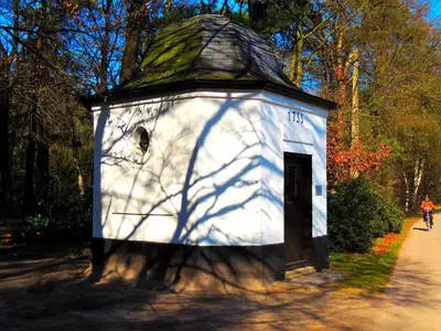 a white building with a roof with a person riding a bike at Hotel Mieke Pap in Poppel