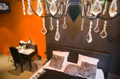 a bedroom with a bed and a desk and a chandelier at Hotel Moon in Sint-Niklaas