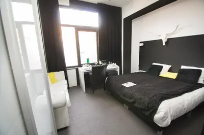 a bedroom with a bed and a desk and a window at Hotel Moon in Sint-Niklaas