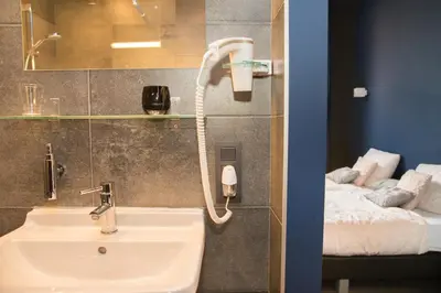 a bathroom with a sink and a phone next to a bed at Hotel Moon in Sint-Niklaas
