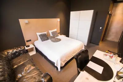 a bedroom with a bed and a couch and a table at Hotel Moon in Sint-Niklaas