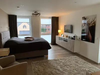 a bedroom with a bed and a television and a chair at Q Studio in Herzele