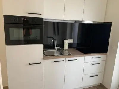 a kitchen with white cabinets and a black microwave at Q Studio in Herzele