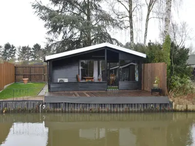 a tiny house on a dock next to a body of water at Modern waterfront chalet in Geel