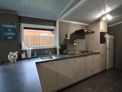 a large kitchen with a sink and a refrigerator at Modern waterfront chalet in Geel