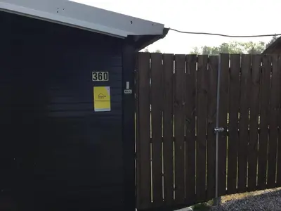 a black building with a sign on it next to a fence at Modern waterfront chalet in Geel