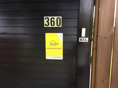 a yellow sign on a black door with a house sign at Modern waterfront chalet in Geel
