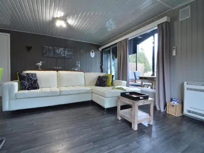 a living room with a white couch and a table at Modern waterfront chalet in Geel