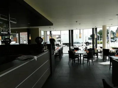 a dining room with tables and chairs and windows at Hotel Otus in Wetteren