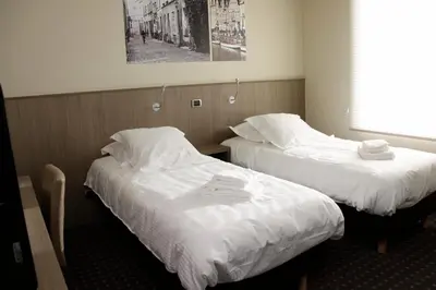 two beds in a hotel room with white sheets at Hotel Otus in Wetteren