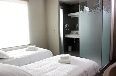 a room with two beds and a bathroom with a mirror at Hotel Otus in Wetteren