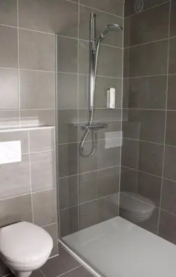 a bathroom with a shower with a toilet and a sink at Hotel Otus in Wetteren