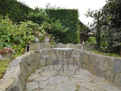 a table and two chairs sitting next to a stone wall at Lovely Holiday Home in Merksplas with Fenced Garden in Merksplas