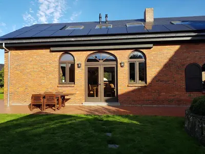 a brick house with solar panels on the roof at Lovely Holiday Home in Merksplas with Fenced Garden in Merksplas