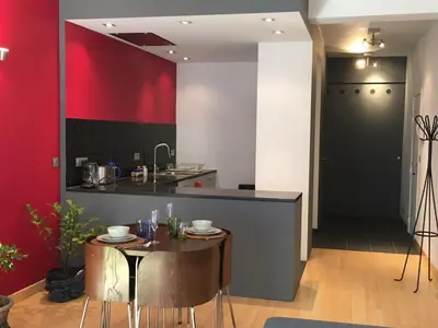 a kitchen with a table and a red wall at Gachard in Brussels