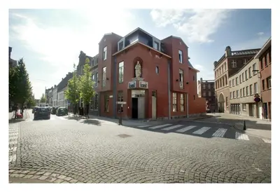a large red brick building on a cobblestone street at Hotel Florent in Lier