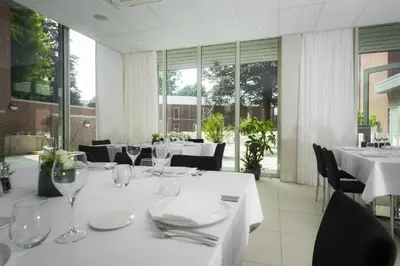 a dining room with white tables and chairs and windows at Hotel Florent in Lier