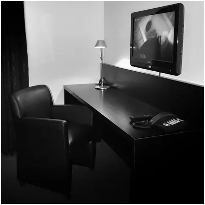 a room with a desk with a television and a chair at Hotel Florent in Lier