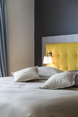 a bedroom with a bed with a yellow headboard and pillows at Hotel In den Bonten Os in Rijmenam