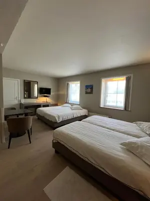 a hotel room with two beds and a desk at Hotel In den Bonten Os in Rijmenam