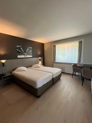 a bedroom with a bed and a desk and a table at Hotel In den Bonten Os in Rijmenam