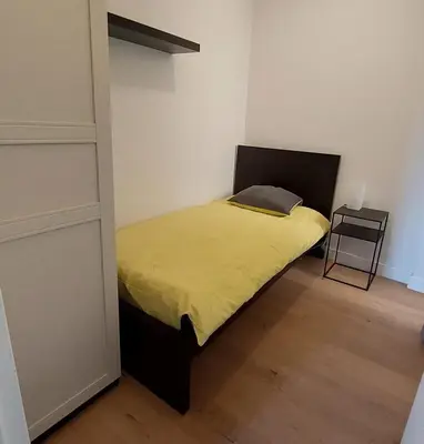 a small bedroom with a bed with a yellow blanket at Astrid - apartments in Mechelen