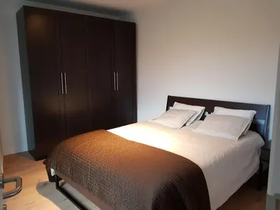 a bedroom with a large bed and a cabinet at Astrid - apartments in Mechelen