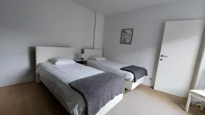 a bedroom with two beds and a door to another room at Astrid - apartments in Mechelen