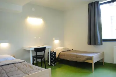 a room with two beds and a table and a desk at Hostel Bruegel in Brussels