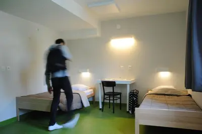 a man walking in a room with two beds at Hostel Bruegel in Brussels