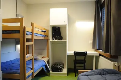 a room with bunk beds and a desk and a chair at Hostel Bruegel in Brussels