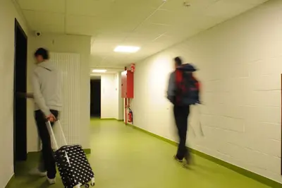 two men walking down a hallway with their luggage at Hostel Bruegel in Brussels