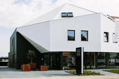 a white building with a gambrel roof at TRUST Hotel in Beveren