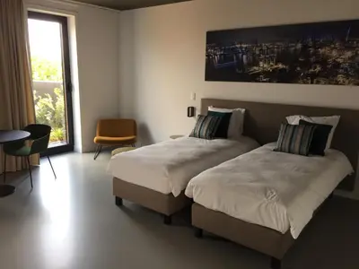 a bedroom with two beds and a table and a window at TRUST Hotel in Beveren