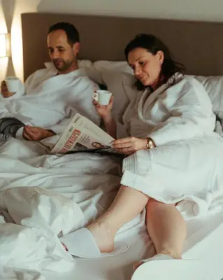 a man and woman sitting in bed reading a newspaper at TRUST Hotel in Beveren