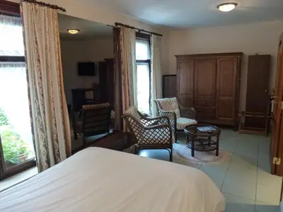 a bedroom with a bed and chairs and windows at Kasteel van Nieuwland in Aarschot