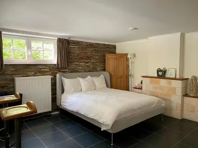 a bedroom with a bed and a brick wall at Studio swimming pool BXL in Dilbeek