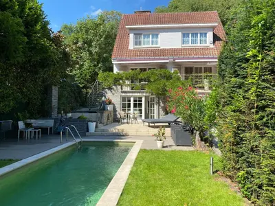 a house with a swimming pool in front of a yard at Studio swimming pool BXL in Dilbeek