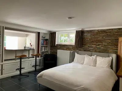 a bedroom with a white bed and a brick wall at Studio swimming pool BXL in Dilbeek